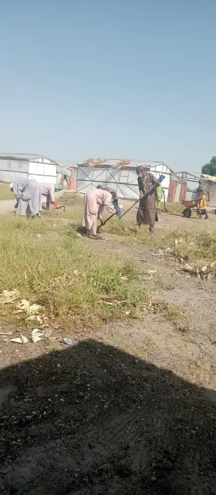 Community members clearing ground around shelters