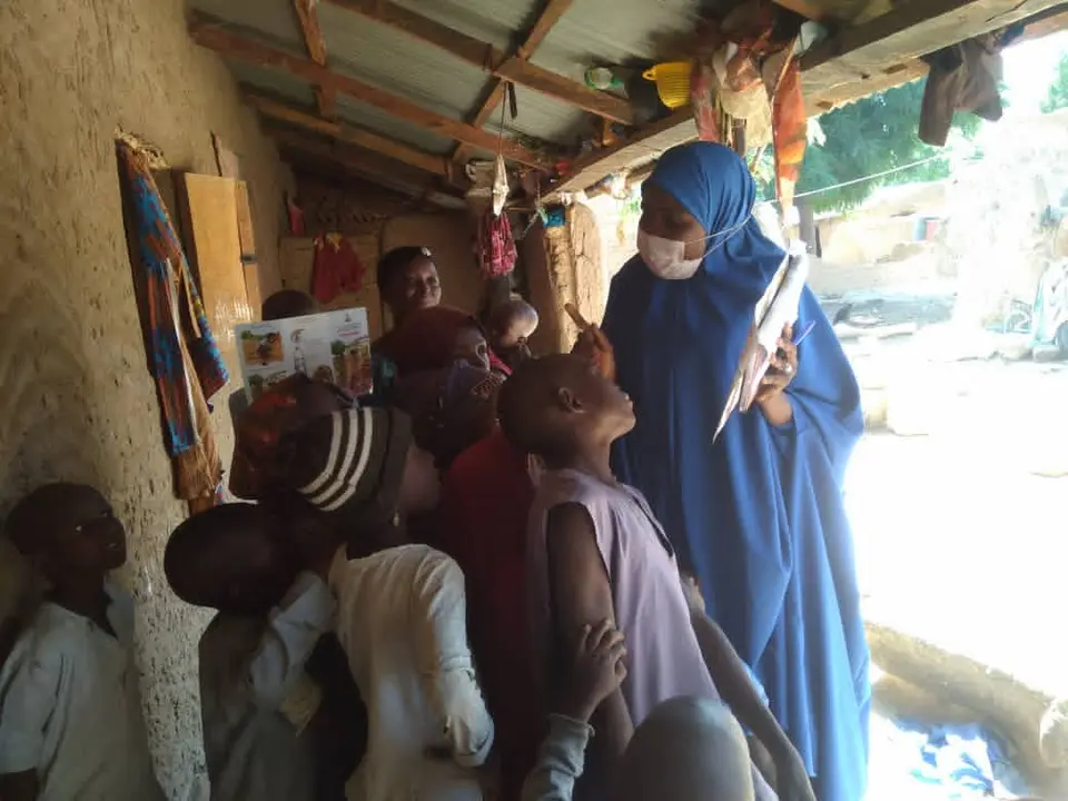 A community health volunteer with a clipboard leads a household session