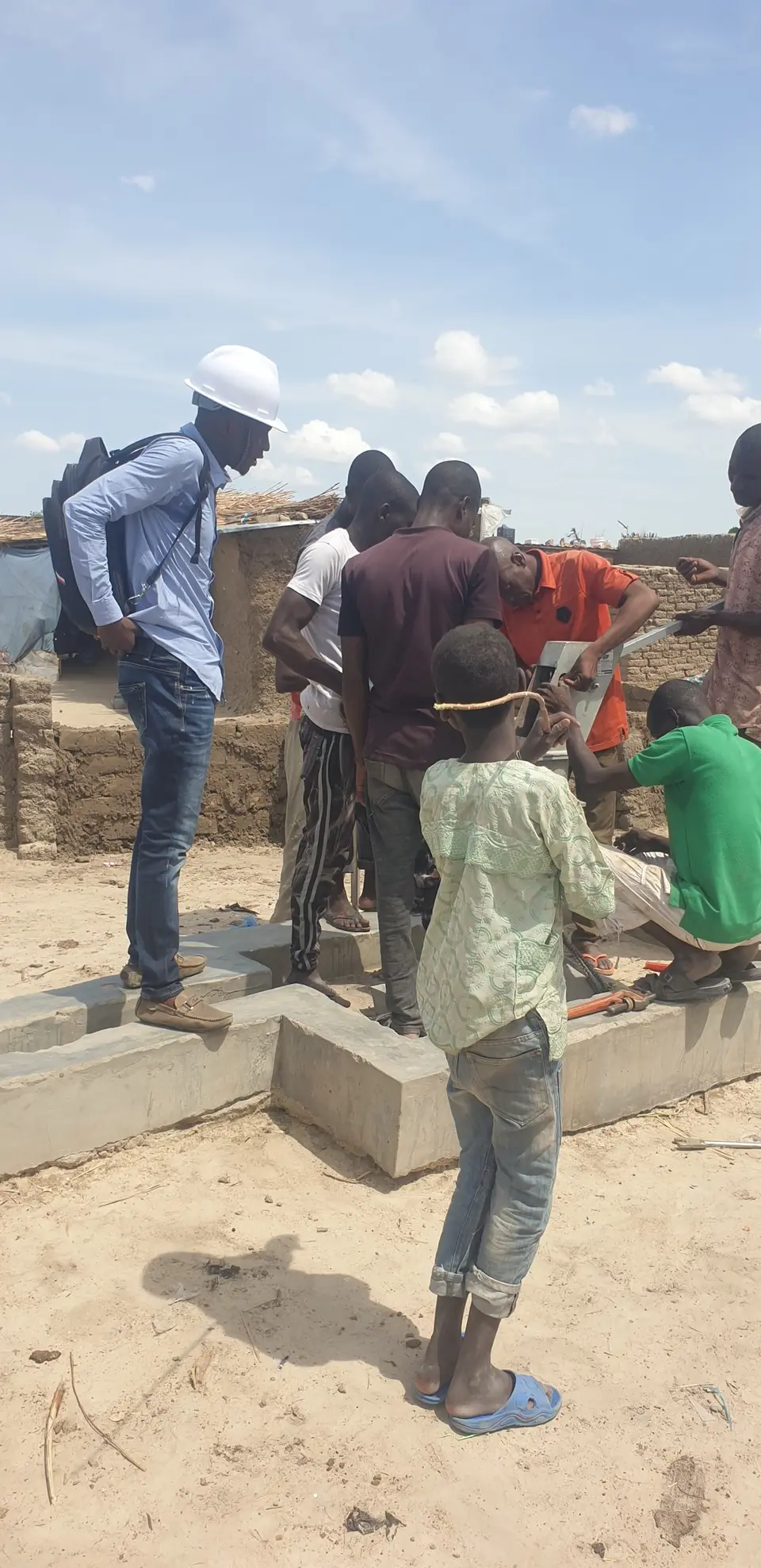 Technicians and community members install a hand pump while an engineer supervises
